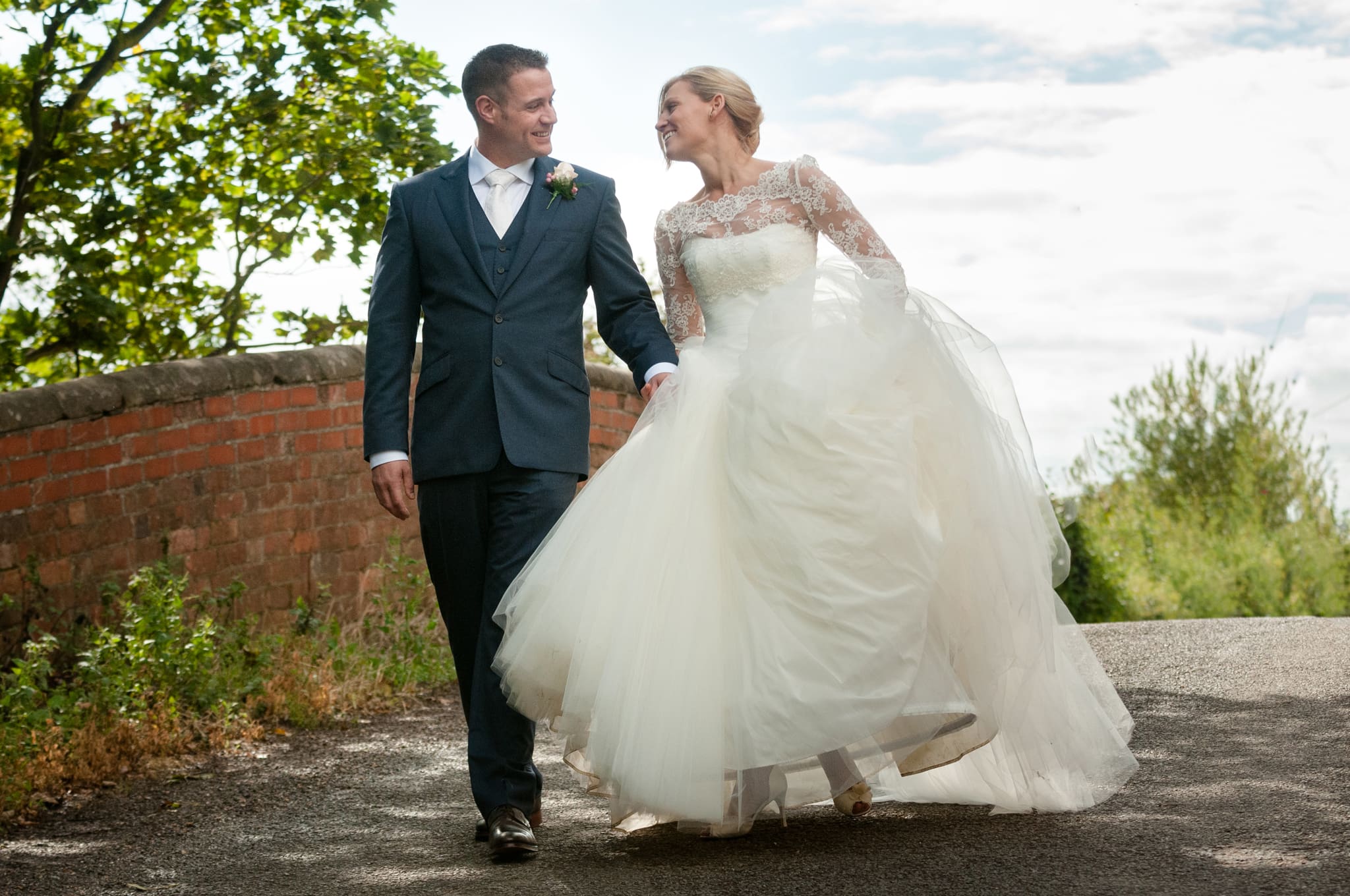 Bride and groom walking over the bridge outside Dodmoor House