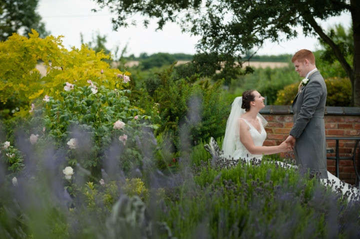 Bride and groom sitting on a bench surrounded by lavender at Dodmoor House
