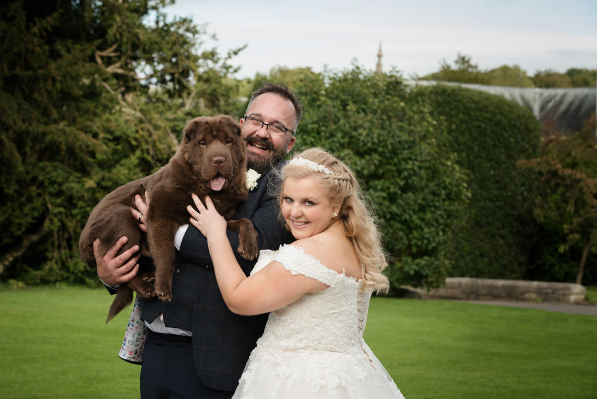 Bride and groom pose for a wedding photo with their dog
