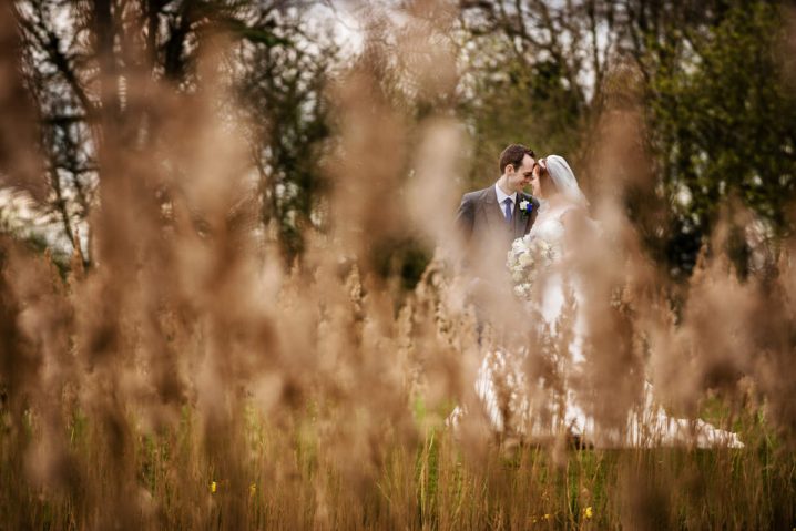 Photo of a bride and groom through long grasses at Chicheley Hall