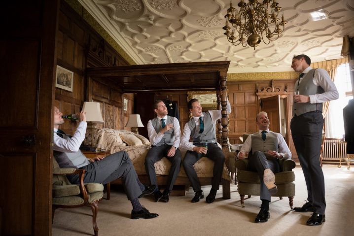 Groomsmen sitting chatting enjoying a drink in the Oak Suite at Rushton Hall
