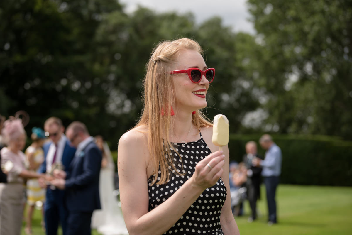 Wedding guest eating a white chocolate magnum at Rushton Hall
