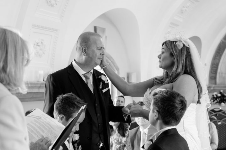 Bride stroking groom's face during ceremony at Normanton Church