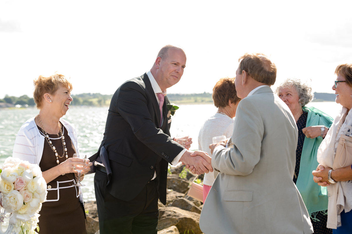 Groom shaking hands with a wedding guest at Normanton Church