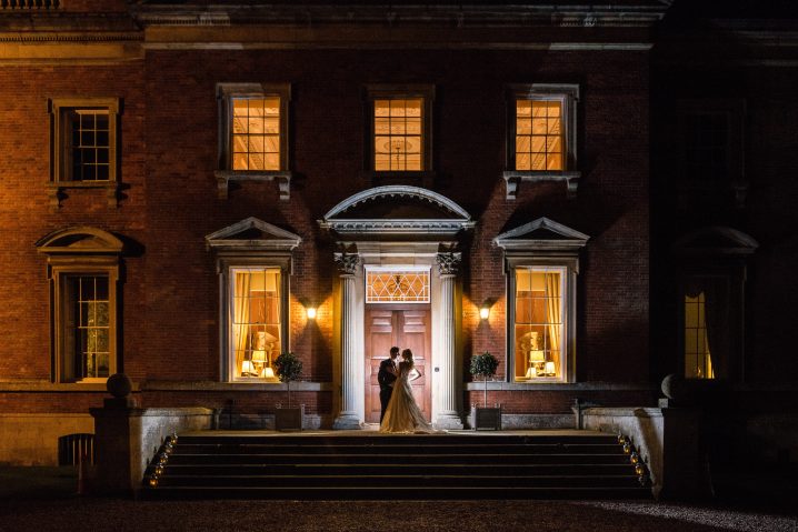 Bride & groom on the front steps of Kelmarsh Hall at night