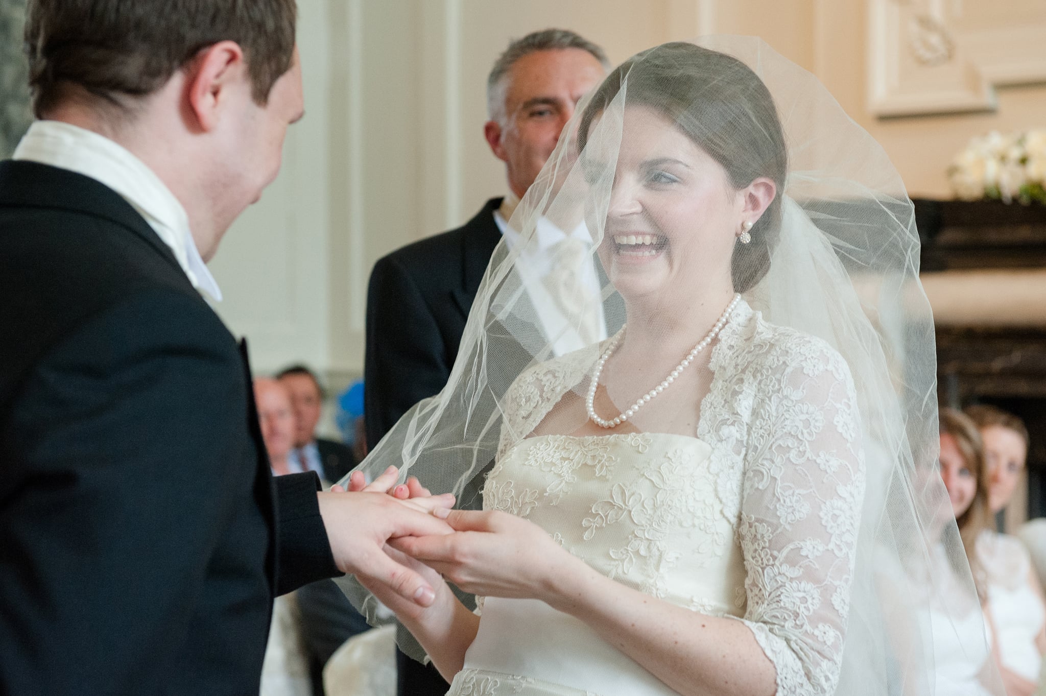 Bride laughing as she tries to put Groom's wedding ring on