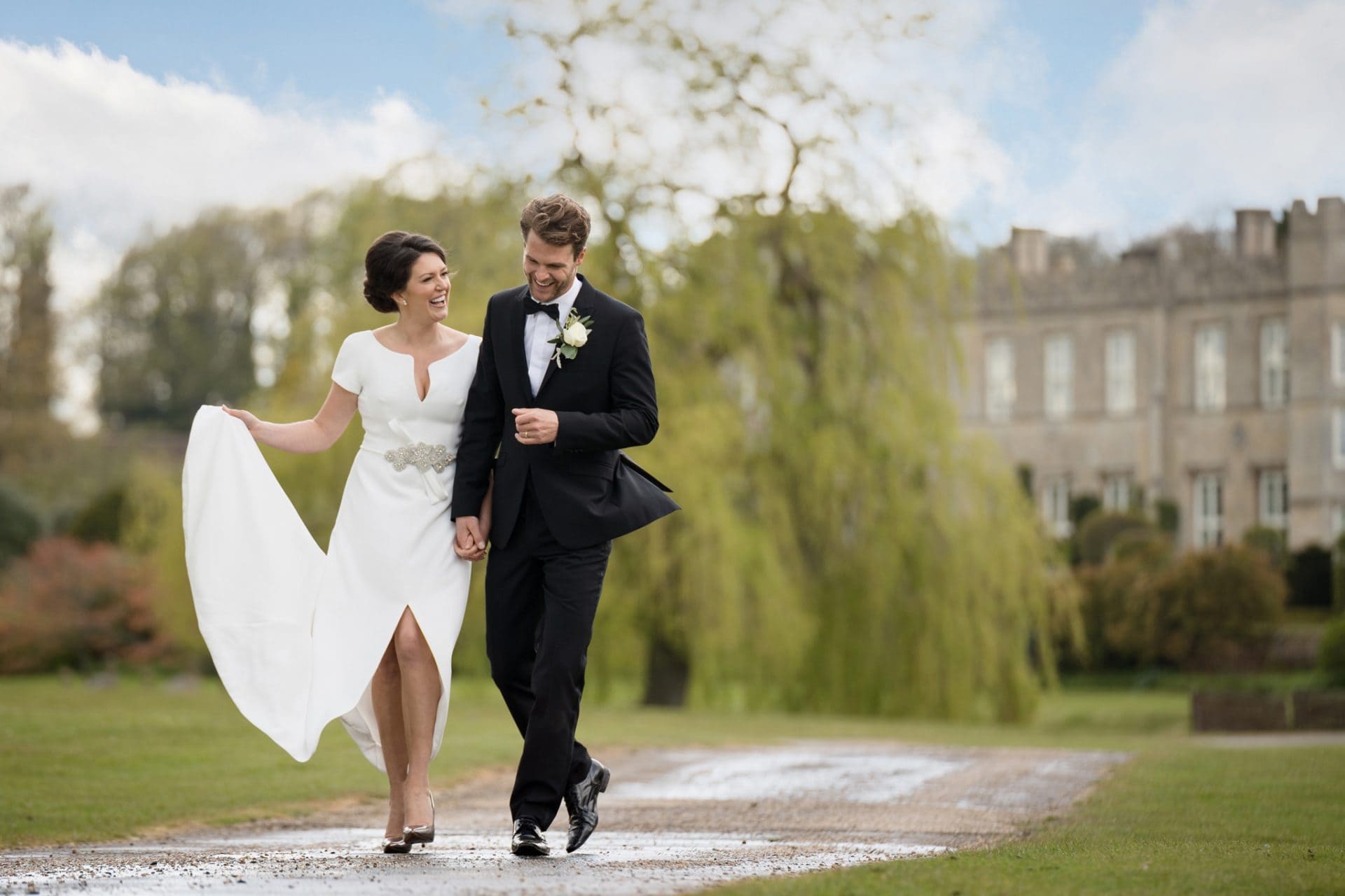 Bride and groom walking in front of the house at Deene Park