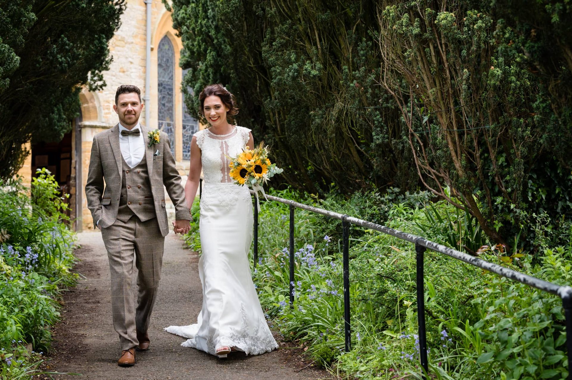 Bride and groom walking down Dallington church path