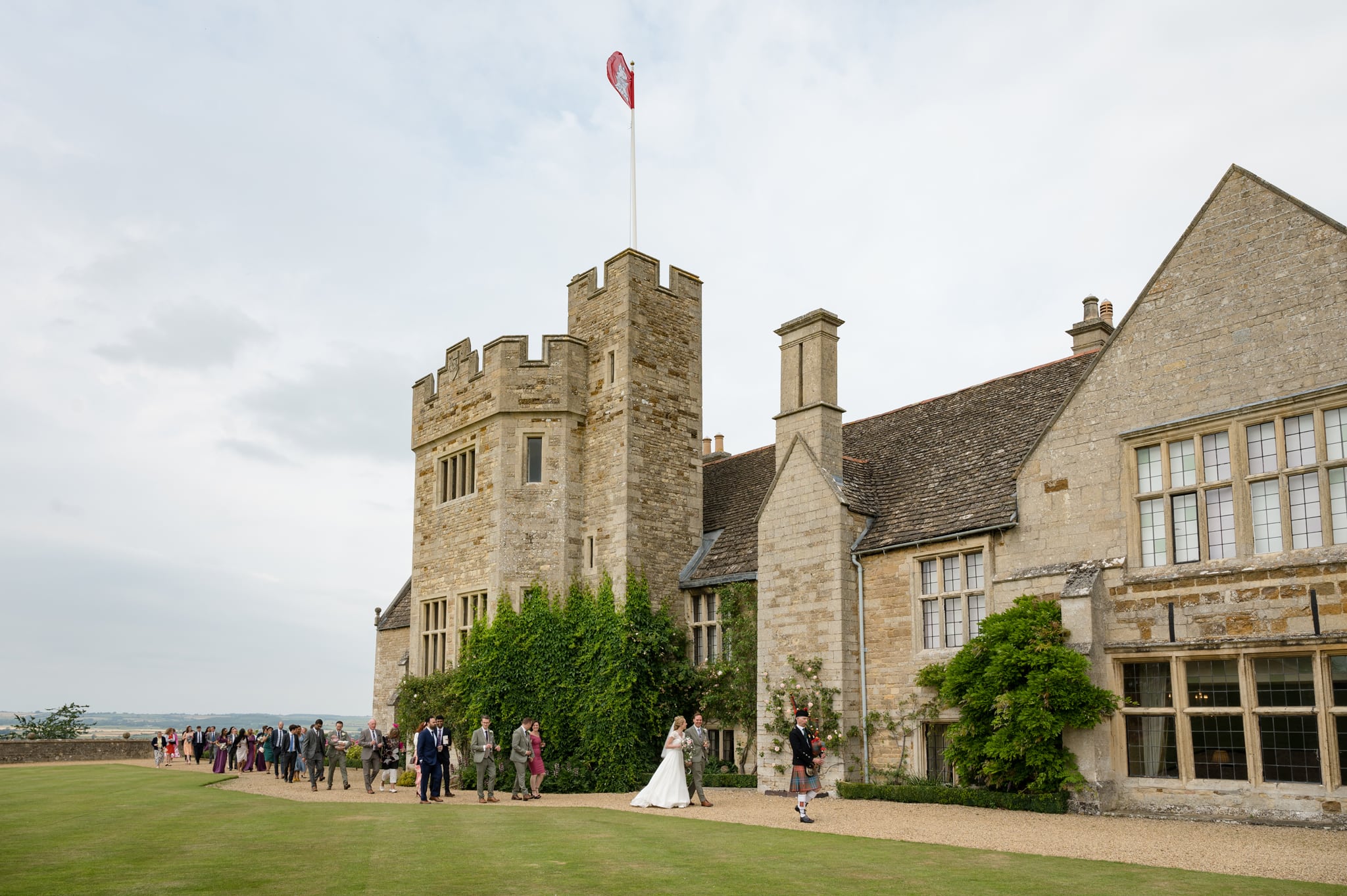 A Scottish bagpiper leading the bride and groom and their guests onto the lawn at Rockingham Castle