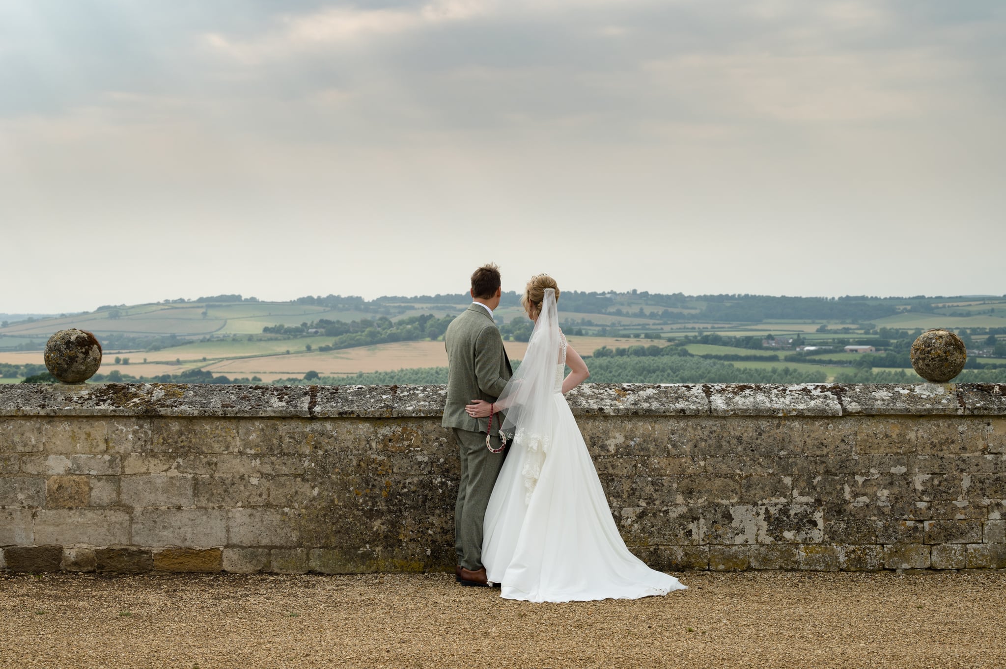 Bride and groom looking out over the Welland Valley from the ramparts at Rockingham Castle
