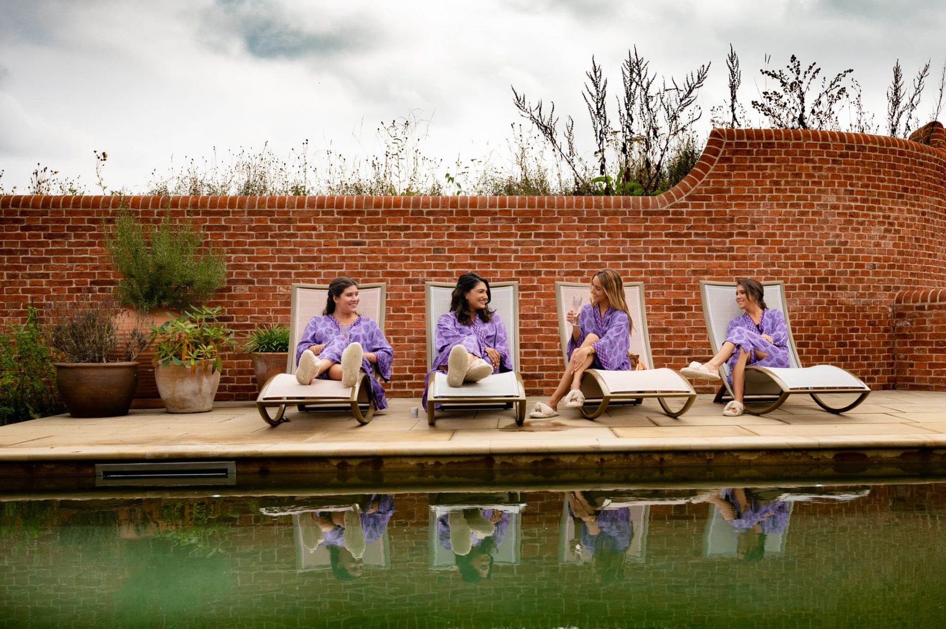 Four bridesmaids in purple robes lounging by pool