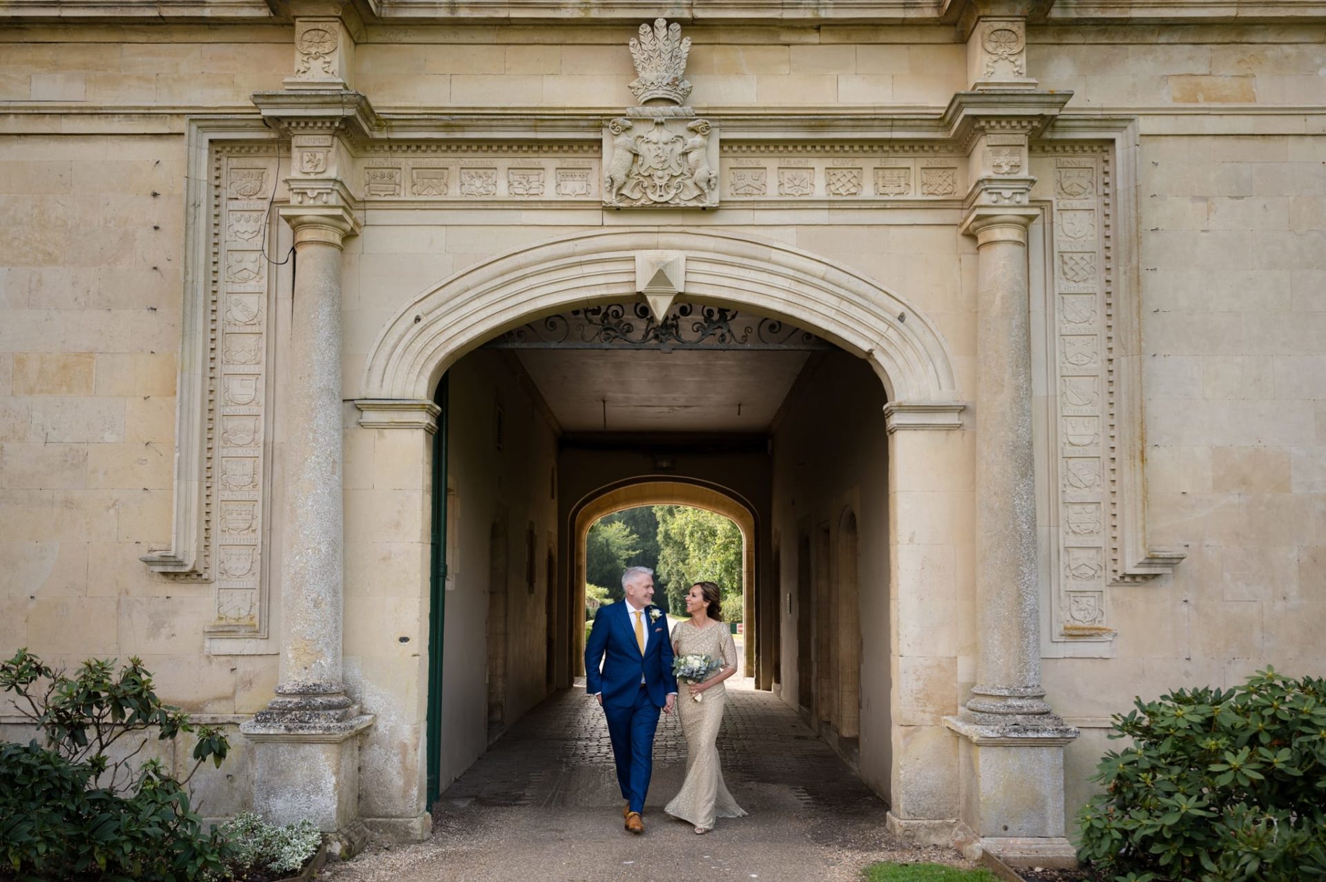 Couple walking under arch carved with decorative family crests
