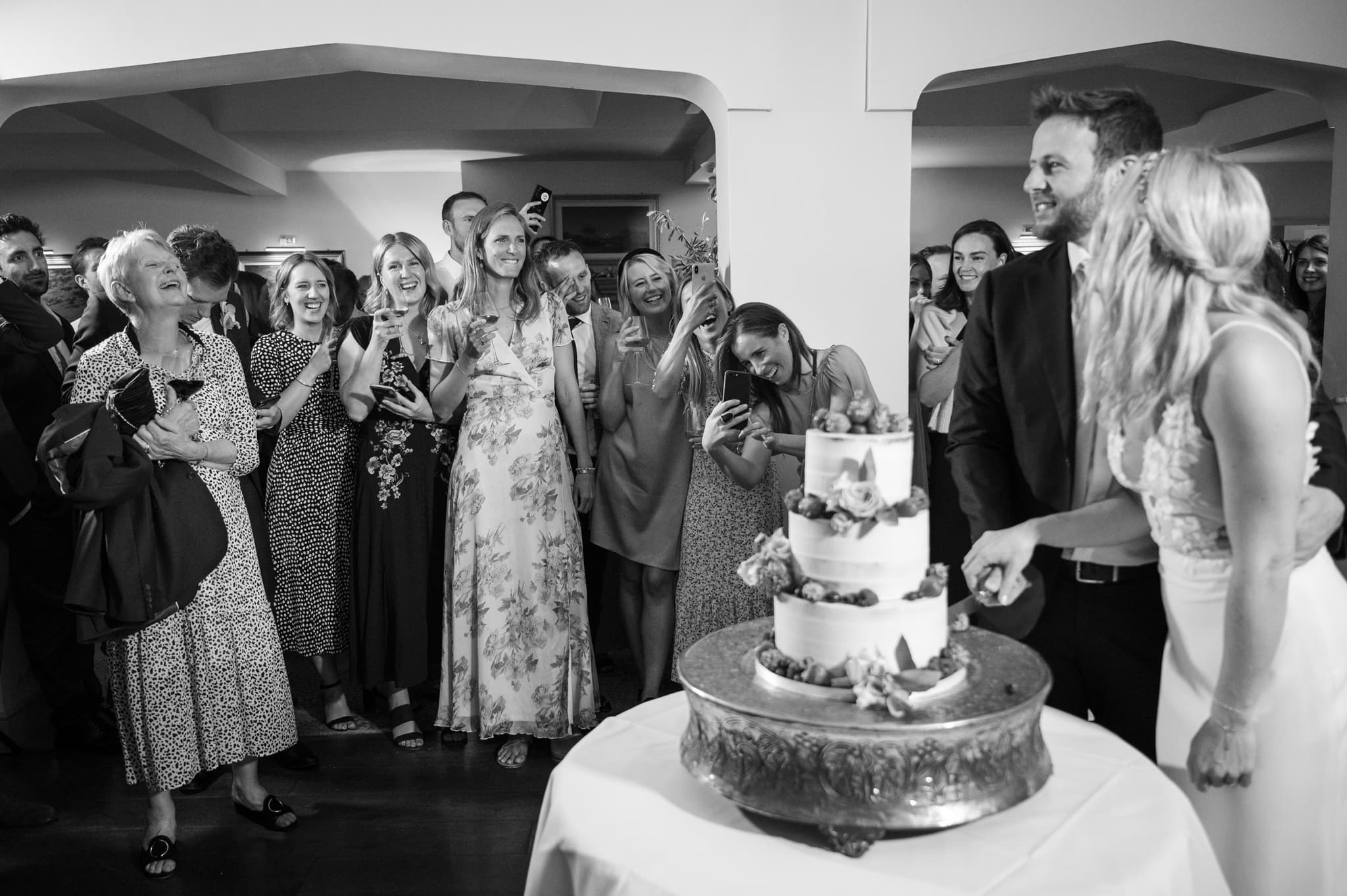 Wedding guests cheering as couple cut cake