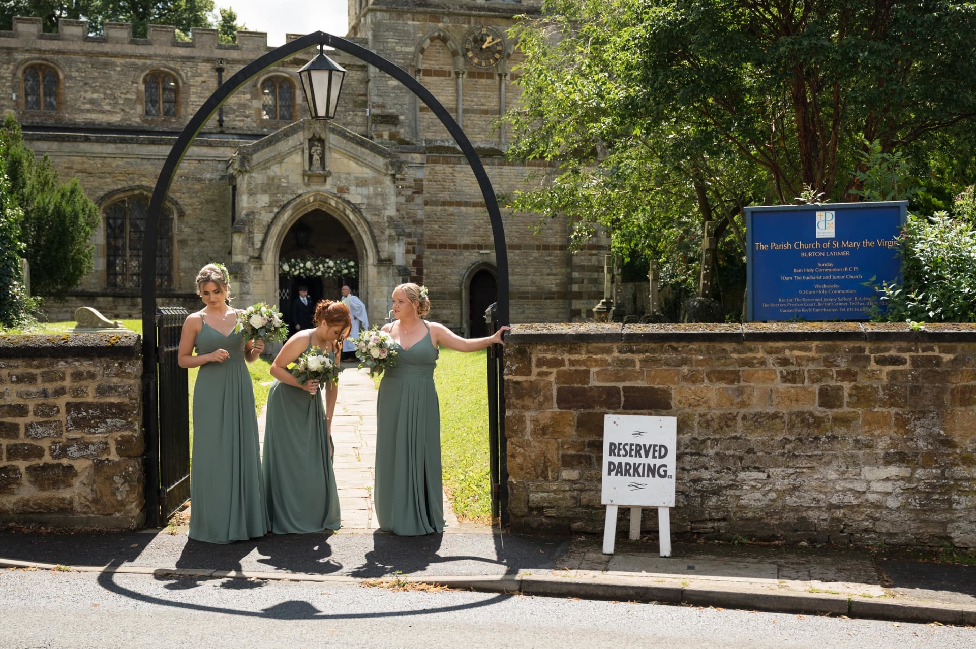 Bridesmaids waiting under arch outside church for bride to arrive