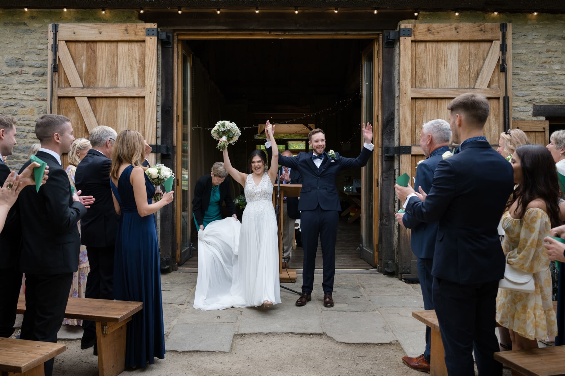 Couple with their arms held high after getting married at The Tythe Barn, Bicester