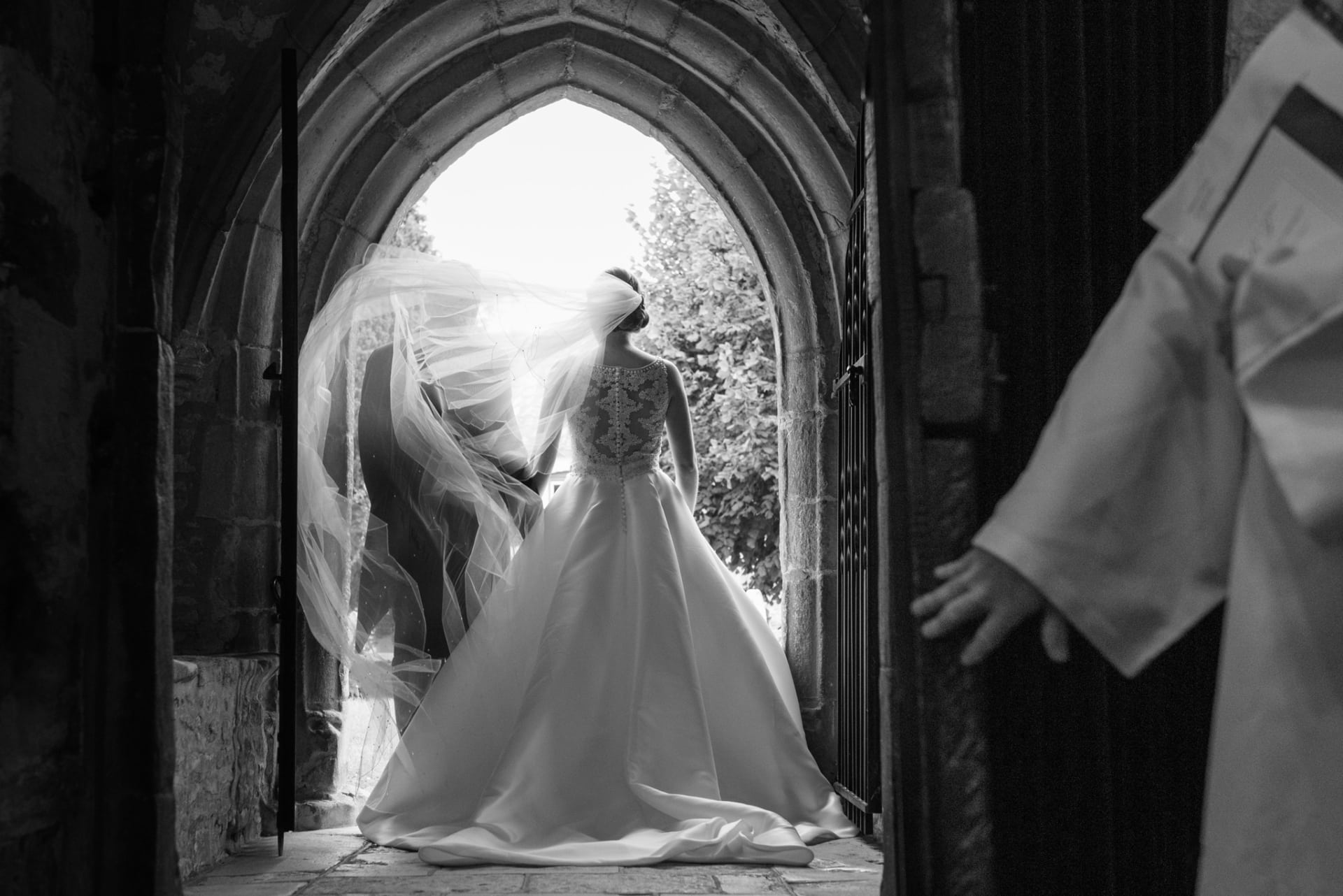 Bride's veil blowing as the couple walk out of church