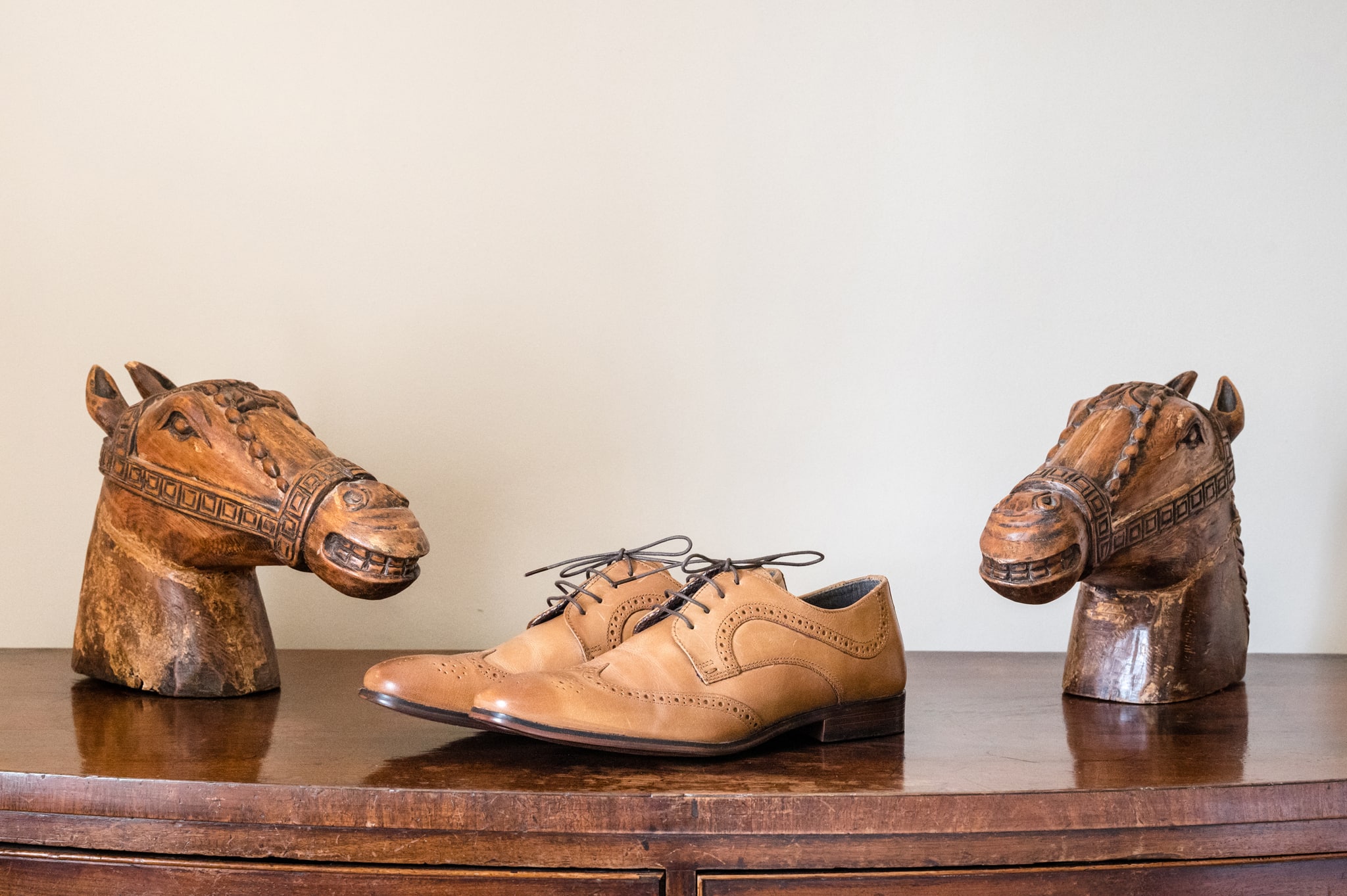 The groom's shoes on top of a chest of drawers between two wooden horse head figures