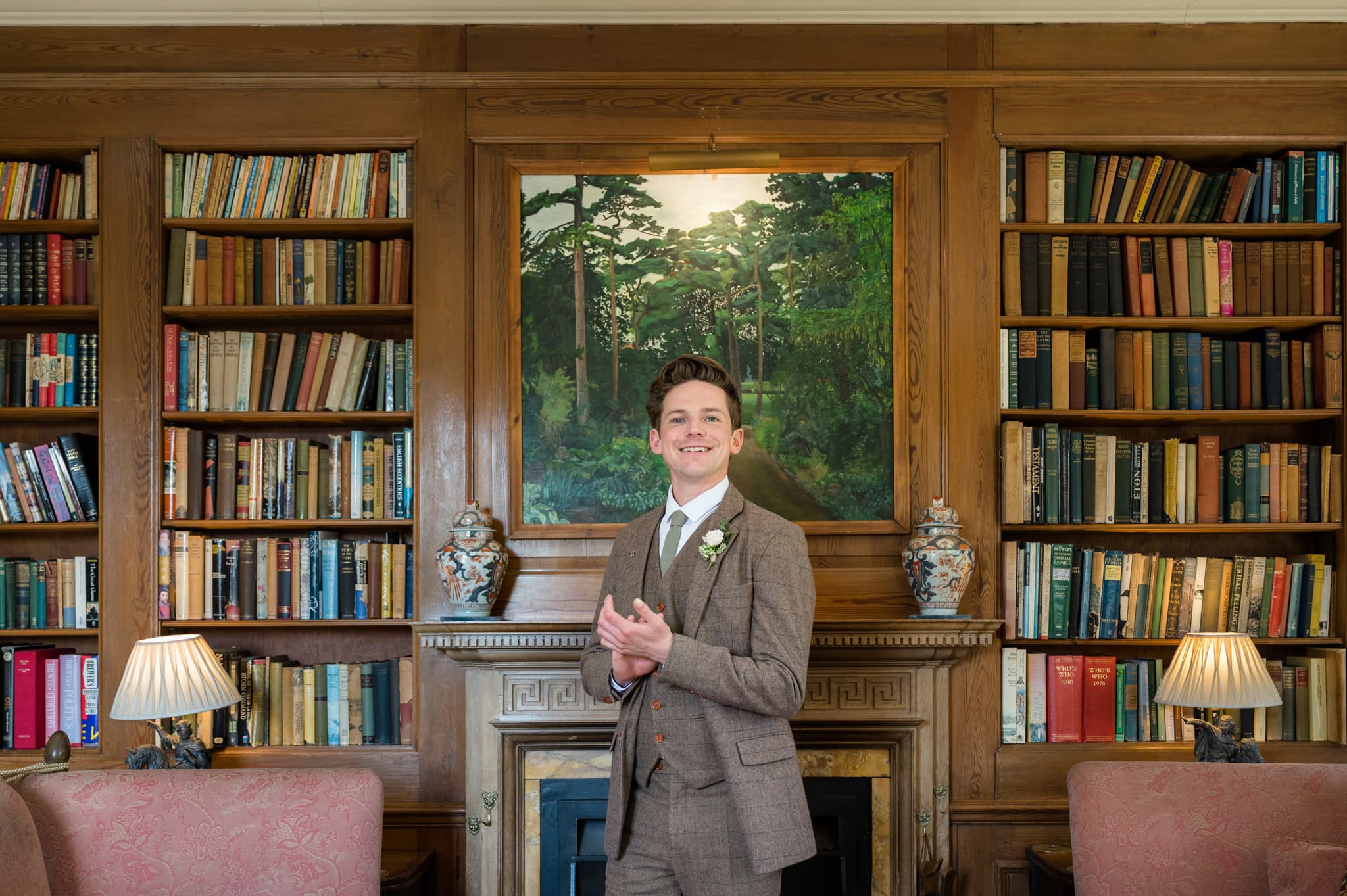 Portrait of the groom in front of a fireplace and bookshelves