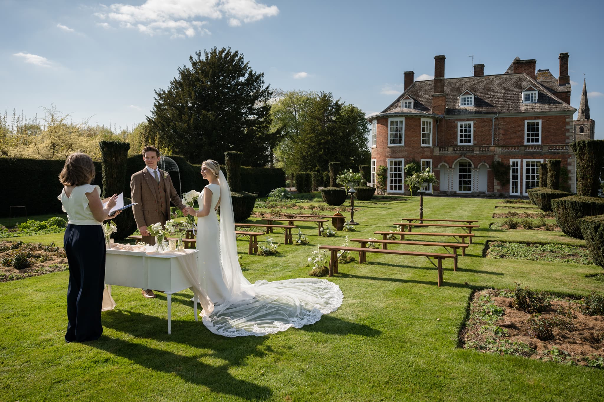 Bride and groom having an outdoor ceremony with Sutton Bonington Hall in the background