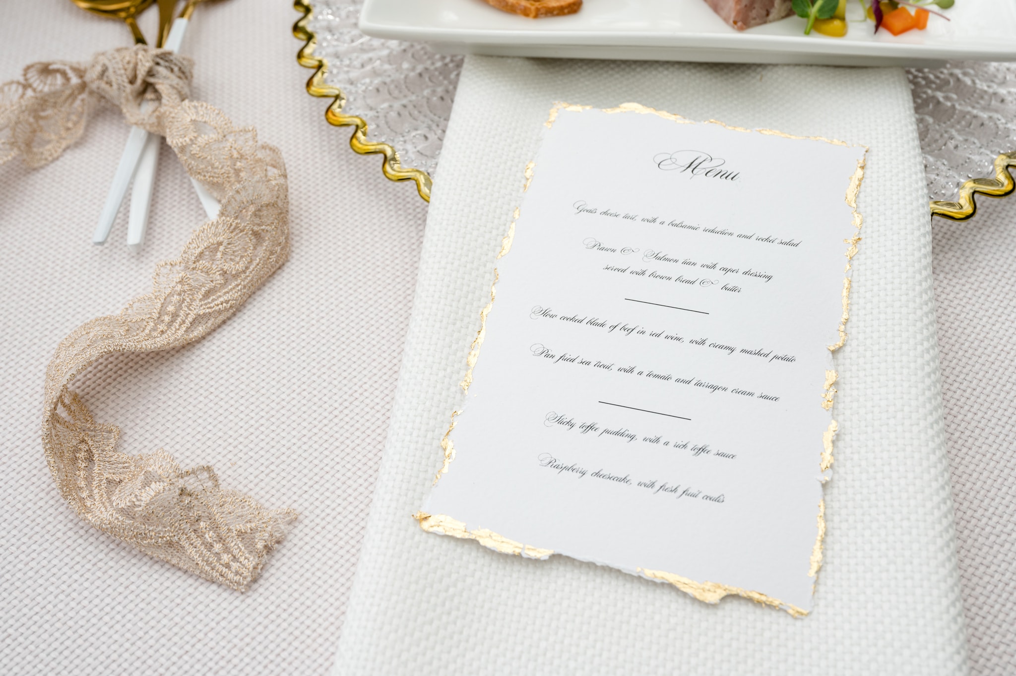 Wedding breakfast menu on plain white paper with a gold leaf and deckled edge