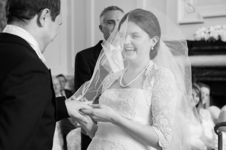 Bride laughing as she tries to put the groom's ring on his finger
