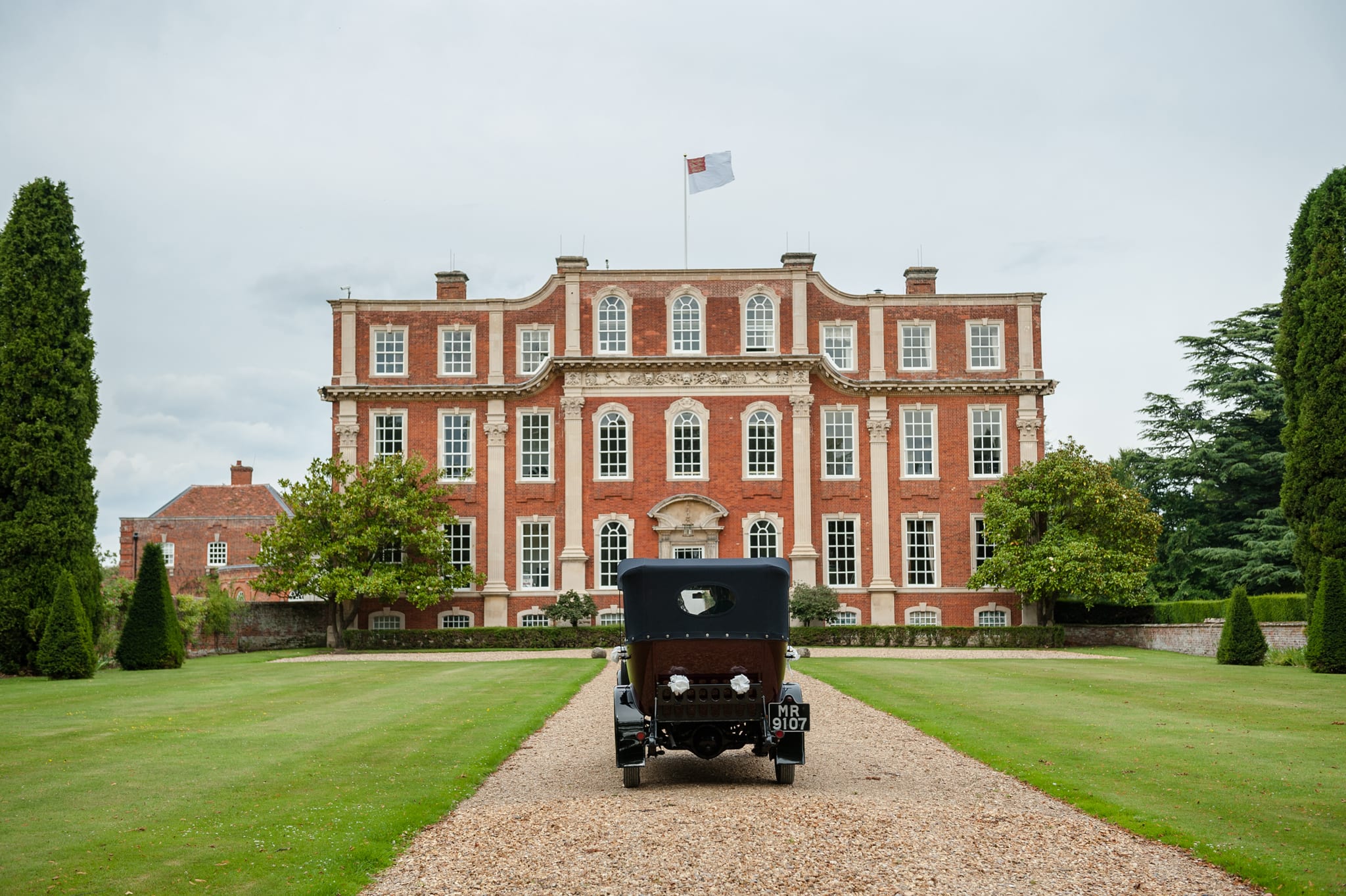 Vintage wedding car driving up to the front of Chicheley Hall