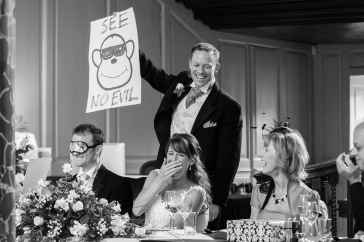 Best Man holding up 'see no evil' sign behind a blindfolded groom during his speech