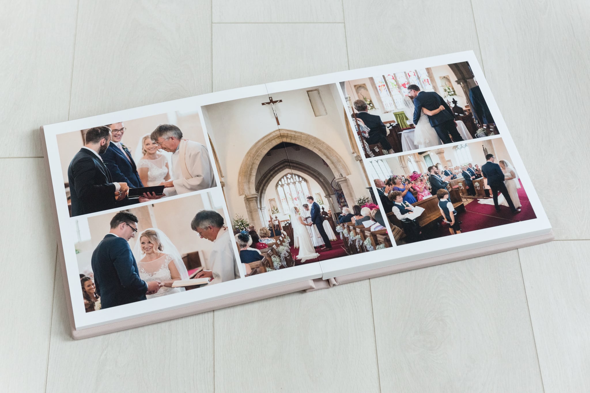 A fine art wedding album opened up and laid on a white wooden floor