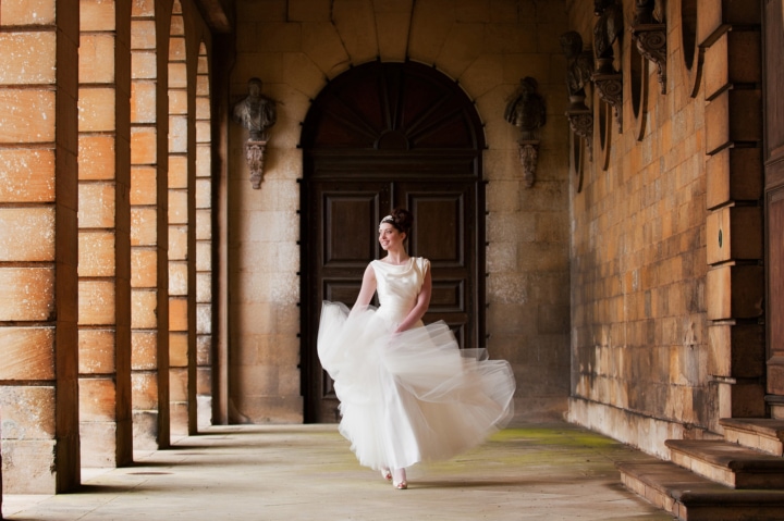 Bride walking under the collonade at Boughton House