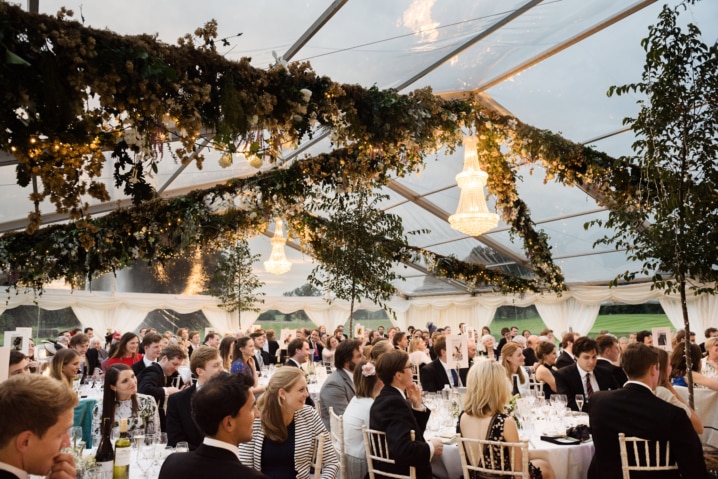 Inside a clear ceiling marquee lit up with chandeliers at dusk