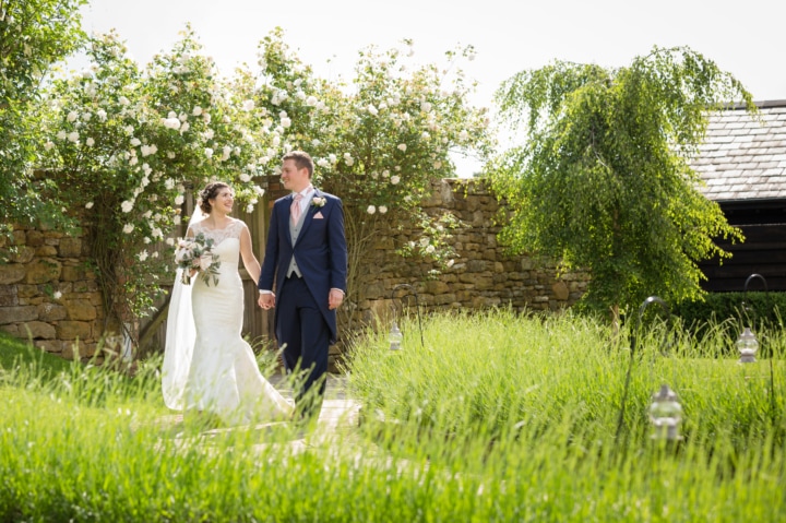 Bride and groom walking through a lavender-lined pathway at Dodford Manor