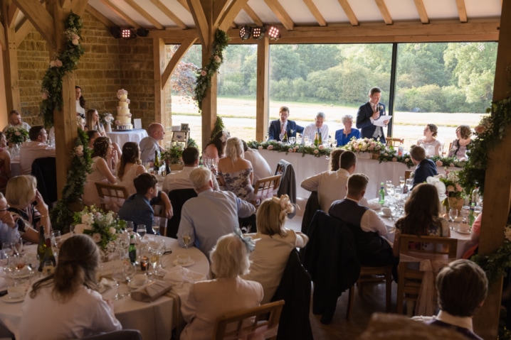 Groom making a speech with big windows behind him at Dodford Manor