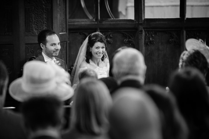Bride and groom smiling back at their wedding guests at Dodford church
