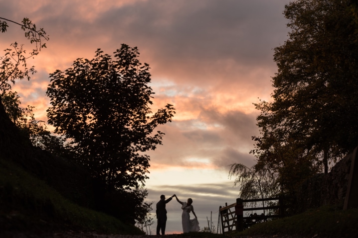 Silhouette of a bride and groom dancing by a gate during sunset at Dodford Manor