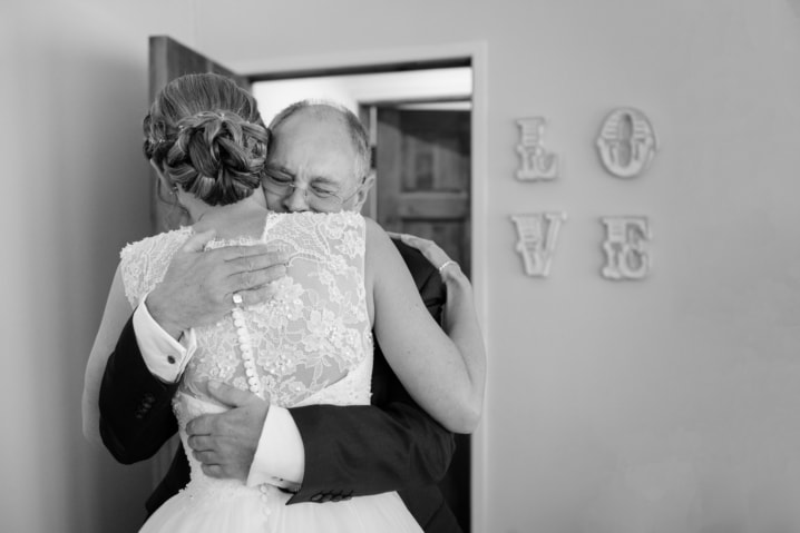 Bride and her dad hugging in front of a LOVE sign at Dodmoor House