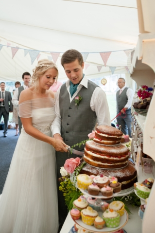 Bride and groom cutting a homemade sponge cake layered with fresh strawberries