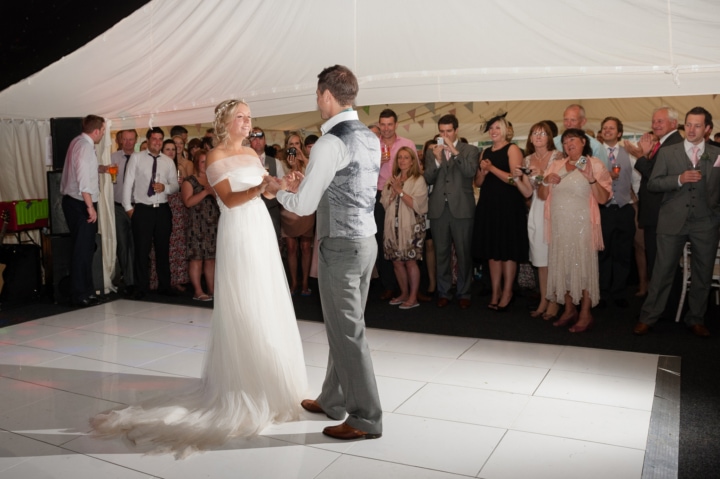 Bride and groom dancing on a white dancefloor in a marquee