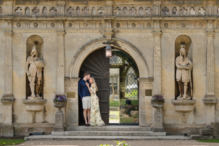 Engaged couple cuddling together at the front door to Rushton Hall