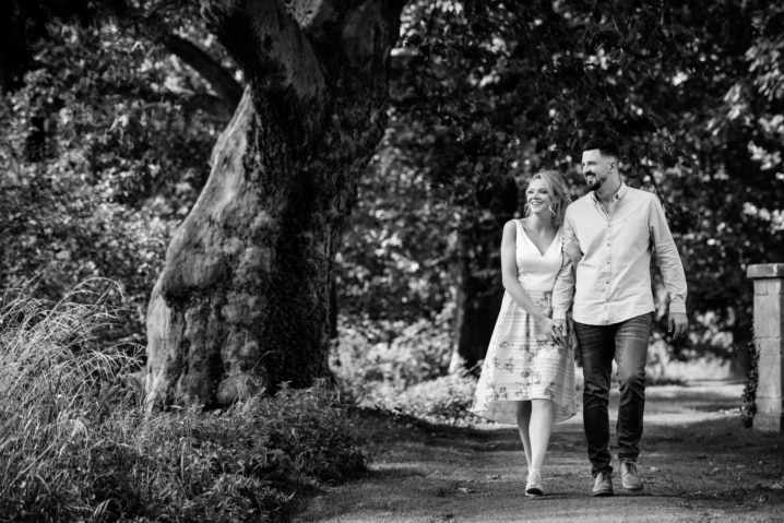 Couple walking hand in hand by the lake at Rushton Hall