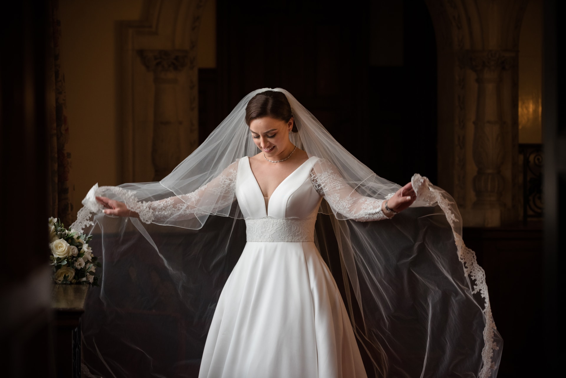 Bride wafting her veil by a window at Rushton Hall
