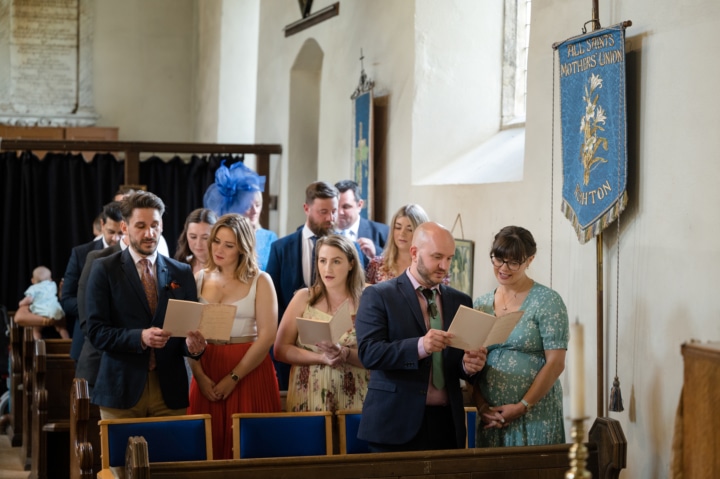 Wedding guests singing hymns at Rushton church
