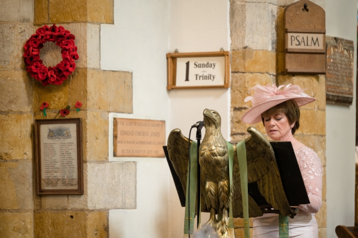 Mother of the bride reading at an eagle lectern at Rushton church