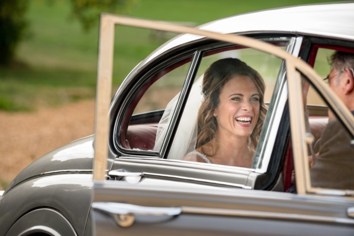 Bride laughing in the back of a vintage wedding car