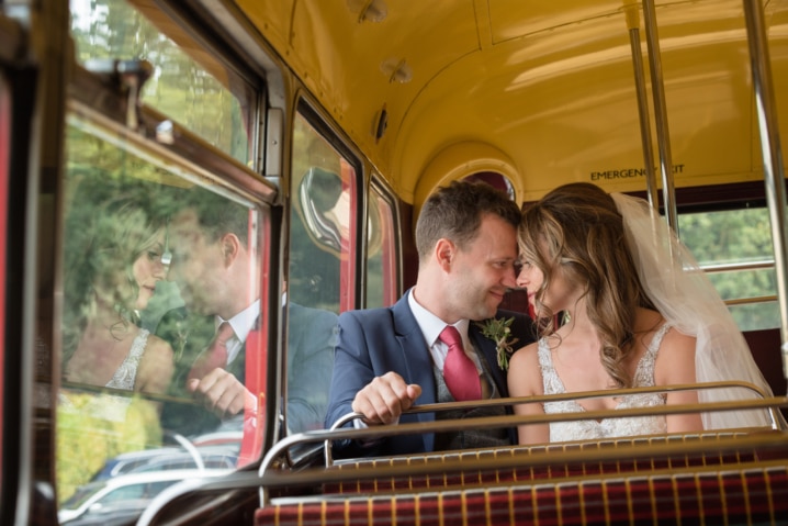 Bride and groom cuddled up on top deck of vintage bus