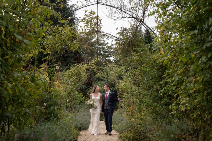 Bride and groom walking under arched walkway of greenery at The William Cecil hotel