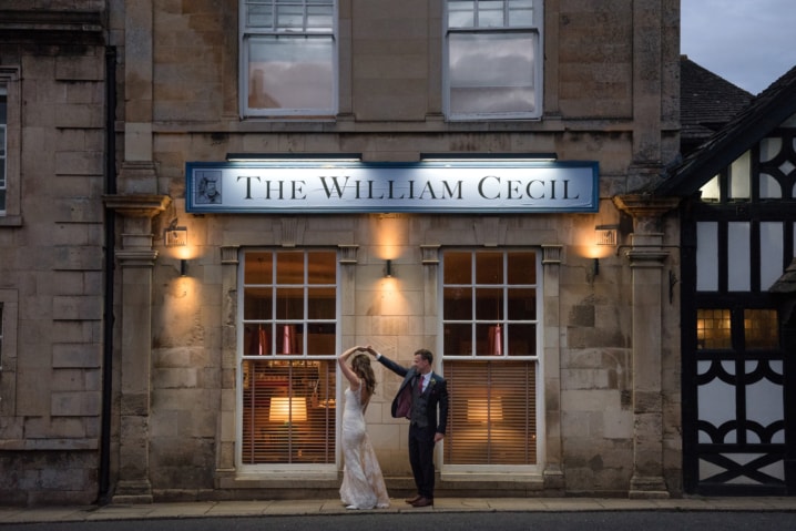 Bride and groom dancing under The William Cecil hotel sign at night