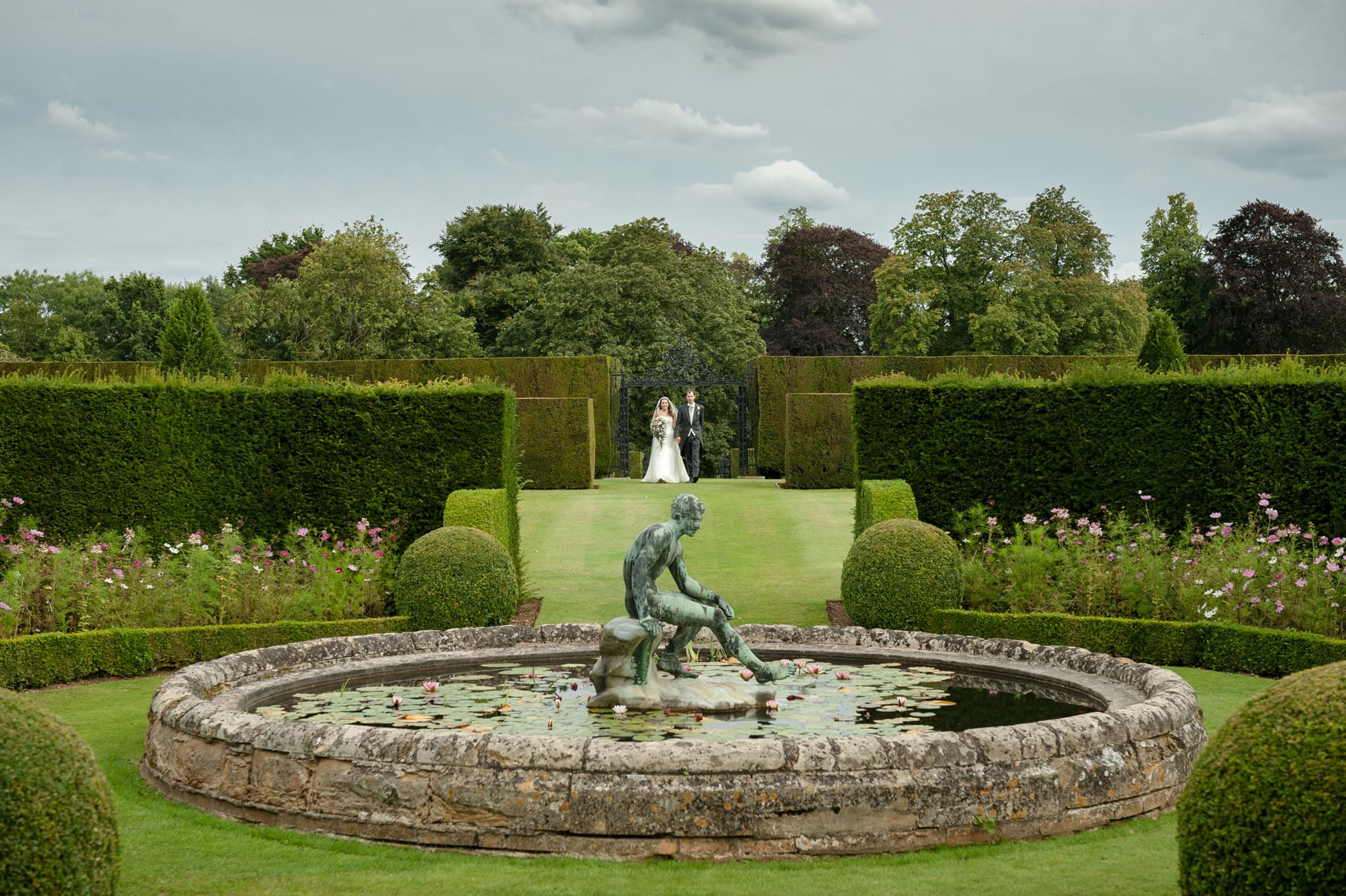 Bride and groom walking to the lily pond at Holdenby House