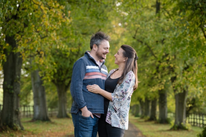 Engaged couple on a tree-lined driveway