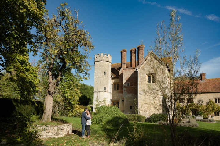 Engaged couple cuddled together in front of Notley Abbey