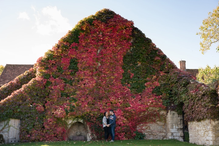 Engaged couple in front of ivy covered wall at Notley Abbey